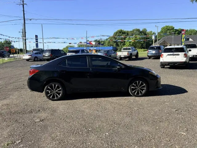 Black car with trees in background