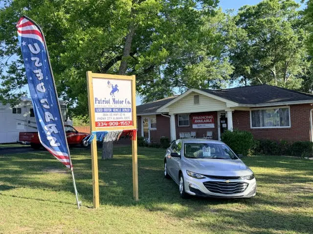 Small dealership with flag and car